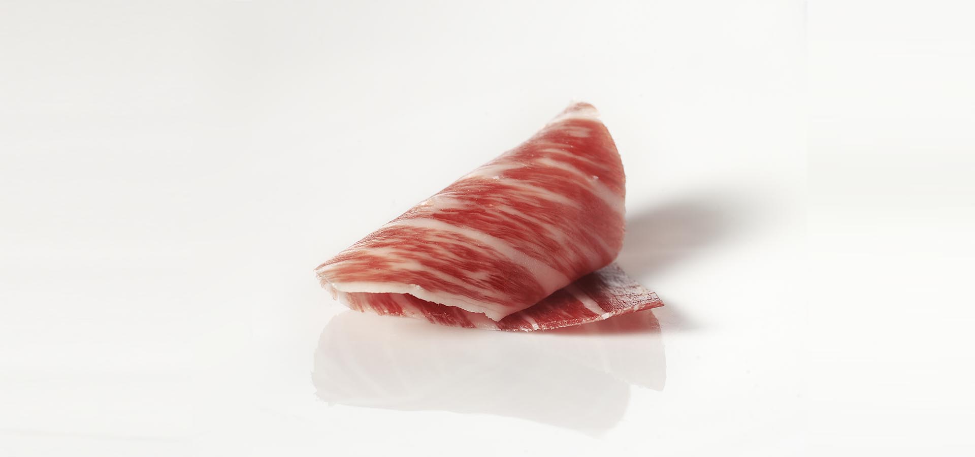 Slice of Acorn-fed Ibérico Shoulder Ham with intense natural marbling.